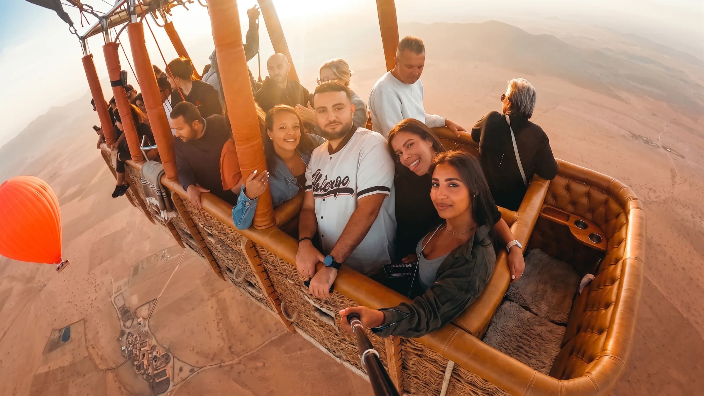 Guests in a leather-padded balloon basket at low sun, the plain far below