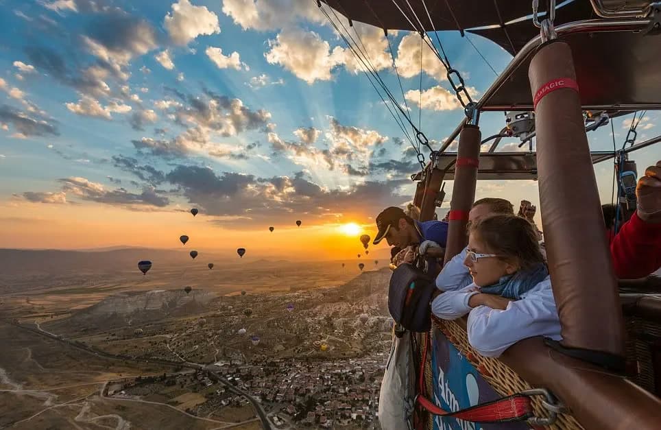 Passengers leaning on the rail of a basket, watching the sun come up